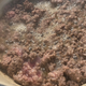 A mushroom beef blend that looks like ground beef is cooking in a pan, with moisture around it.